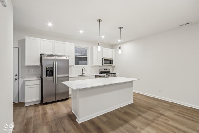 kitchen featuring a center island, pendant lighting, sink, stainless steel appliances, and white cabinets