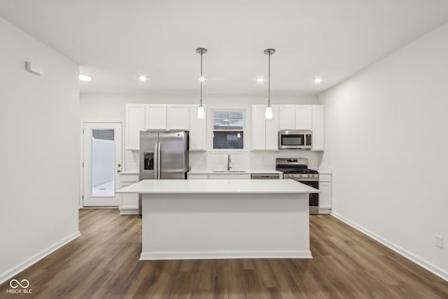 kitchen with hanging light fixtures, appliances with stainless steel finishes, a kitchen island, and sink