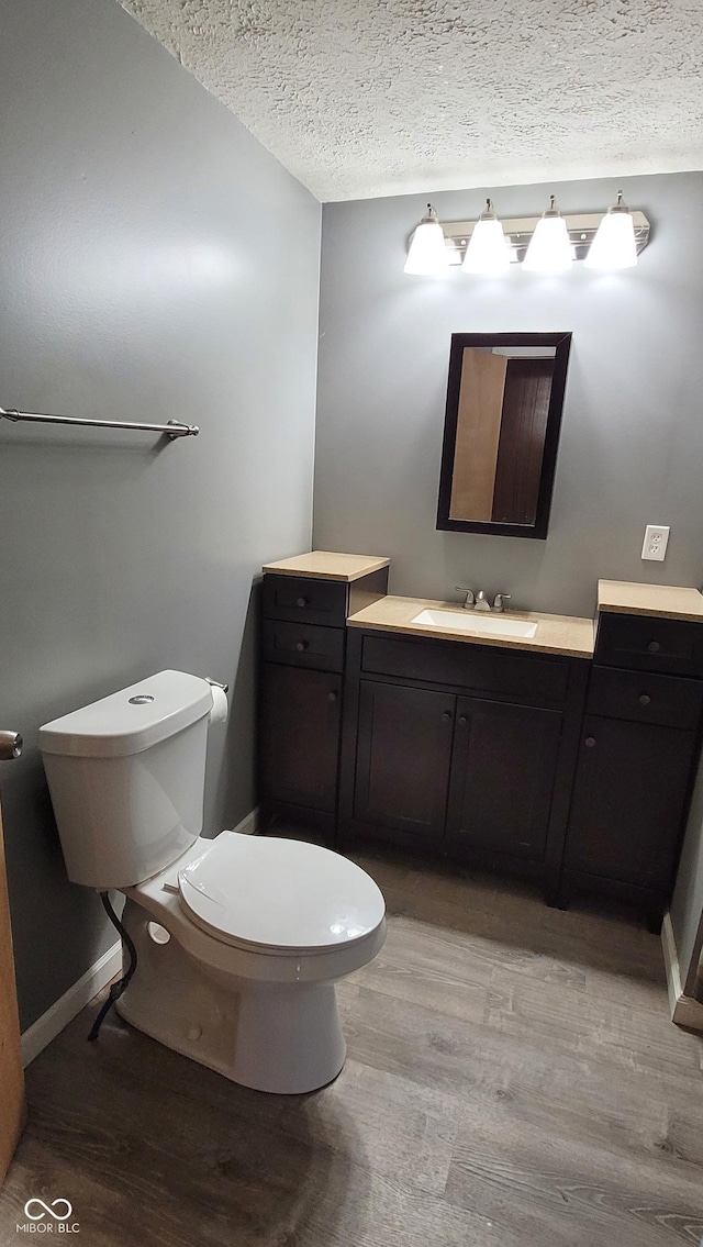 bathroom featuring toilet, a textured ceiling, hardwood / wood-style floors, and vanity