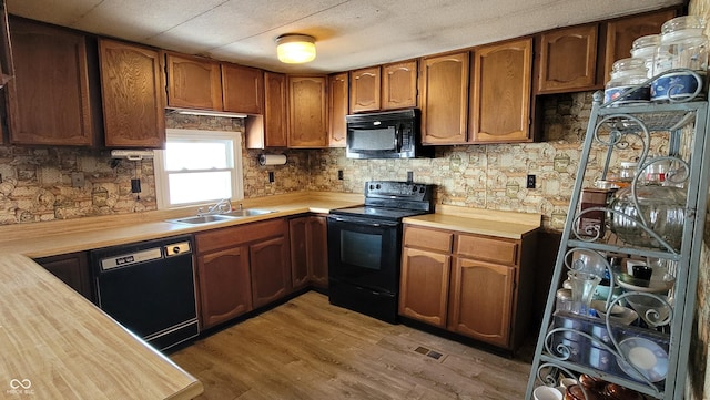 kitchen featuring black appliances, hardwood / wood-style floors, wooden counters, backsplash, and sink