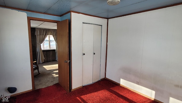 unfurnished bedroom with dark colored carpet and a closet