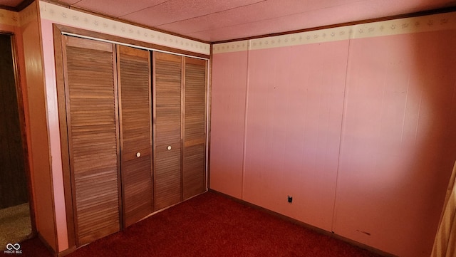 unfurnished bedroom with a closet and dark colored carpet