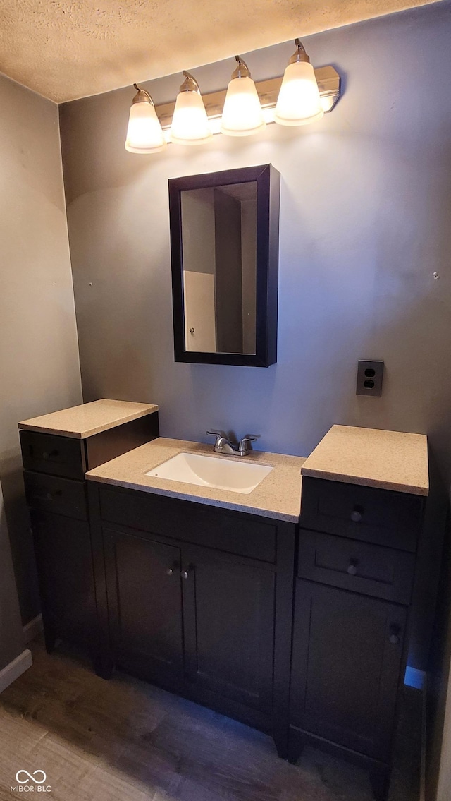 bathroom with wood-type flooring, vanity, and a textured ceiling