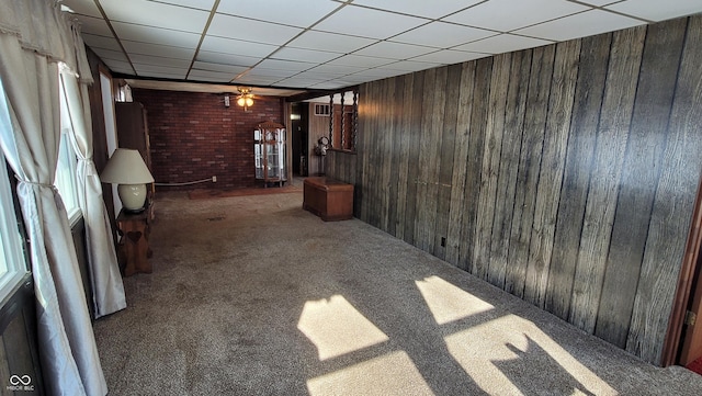 unfurnished living room featuring wood walls, brick wall, and dark colored carpet