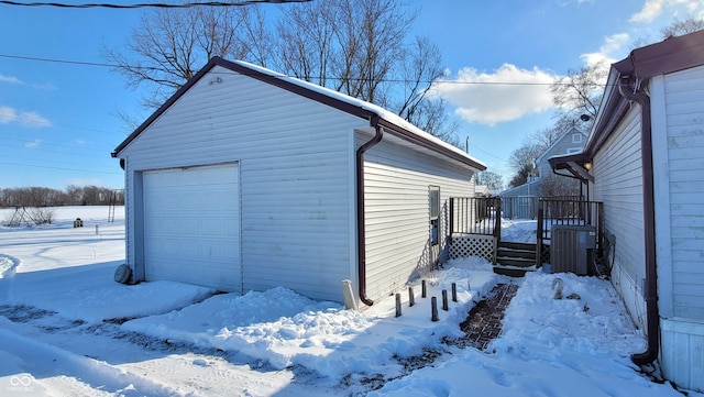 snow covered garage featuring cooling unit