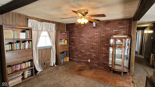 interior space featuring wood walls, beamed ceiling, ceiling fan, carpet flooring, and a textured ceiling