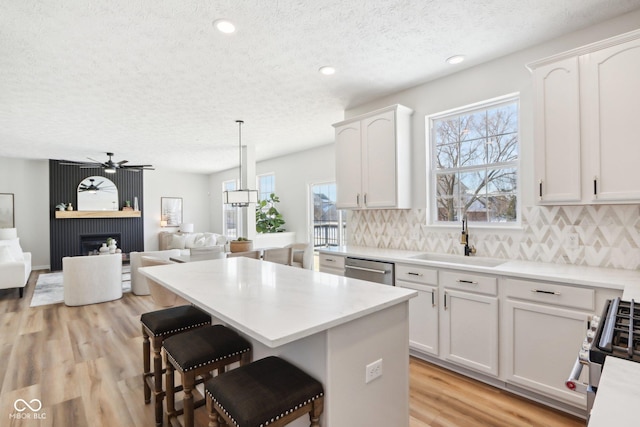 kitchen with decorative backsplash, white cabinetry, sink, and hanging light fixtures