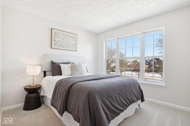 bedroom featuring light colored carpet, a textured ceiling, and multiple windows