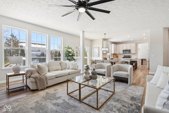 living room featuring ceiling fan, hardwood / wood-style floors, and a textured ceiling