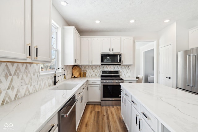 kitchen featuring white cabinets, light stone counters, sink, and stainless steel appliances