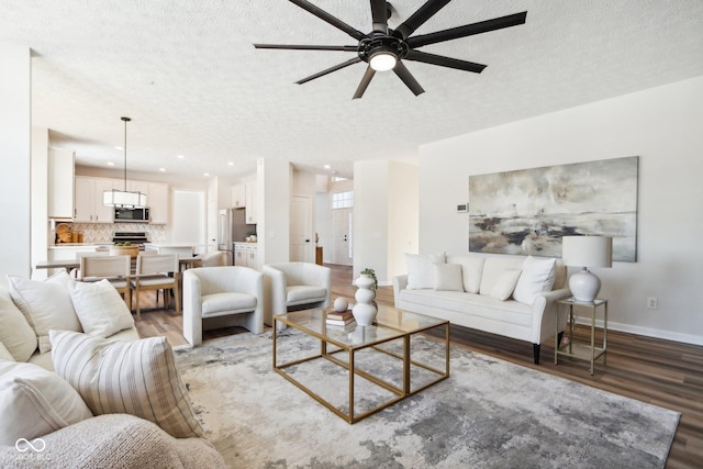 living room featuring ceiling fan, a textured ceiling, and dark wood-type flooring