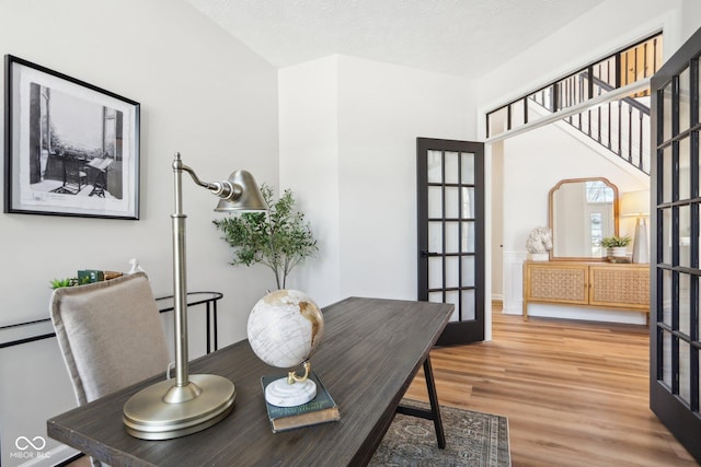 dining space featuring french doors, wood-type flooring, and a textured ceiling