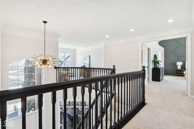 corridor with light colored carpet, ornamental molding, a textured ceiling, and an inviting chandelier