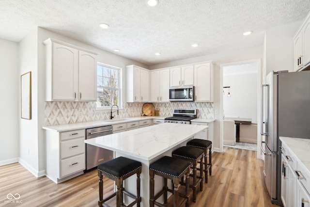 kitchen with a center island, sink, stainless steel appliances, a breakfast bar, and white cabinets