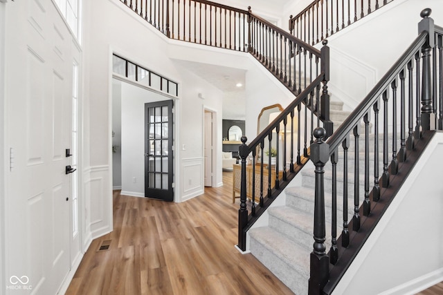 foyer with wood-type flooring and a towering ceiling