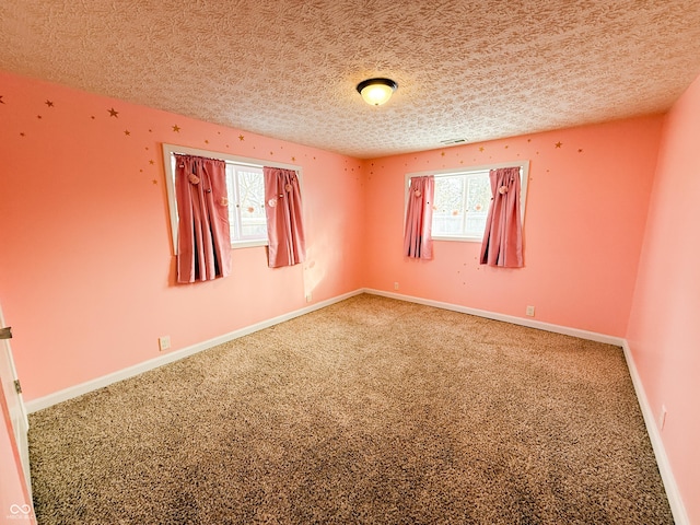 empty room featuring carpet floors, visible vents, a textured ceiling, and baseboards