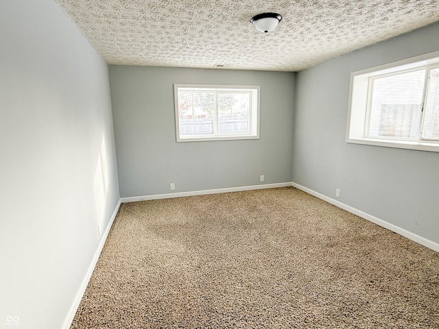 carpeted empty room featuring a textured ceiling and baseboards