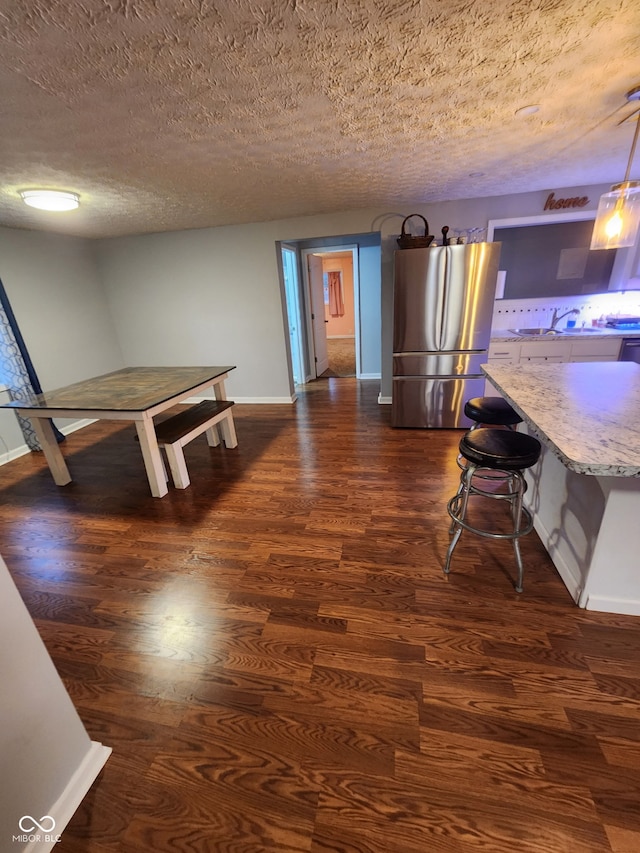 dining space with a textured ceiling, baseboards, and dark wood-type flooring