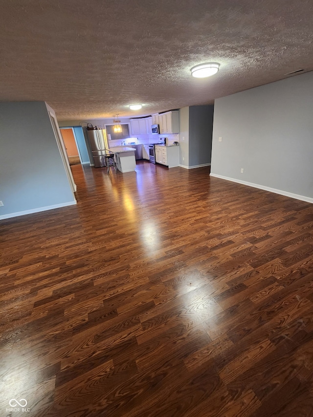 interior space with dark wood finished floors, a textured ceiling, and baseboards