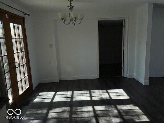 unfurnished dining area with french doors, dark wood-type flooring, and a chandelier