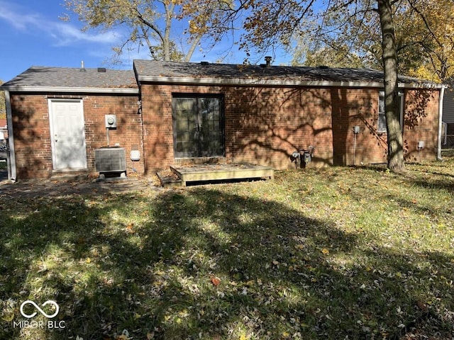 back of house featuring central air condition unit and a lawn