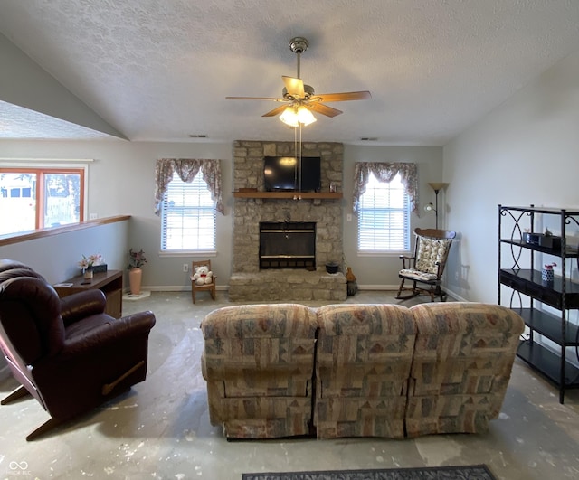 living room with a textured ceiling, ceiling fan, a fireplace, and vaulted ceiling