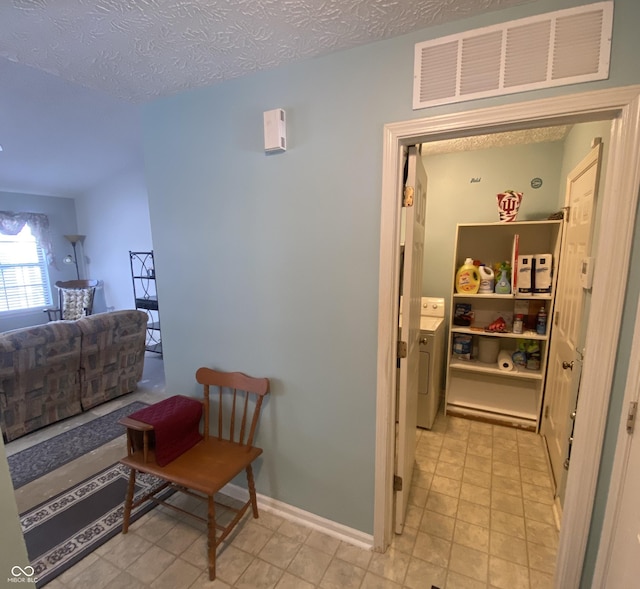 hall featuring washer / clothes dryer and a textured ceiling