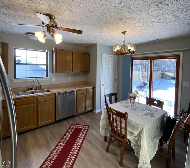 kitchen featuring appliances with stainless steel finishes, ceiling fan with notable chandelier, sink, hardwood / wood-style flooring, and hanging light fixtures