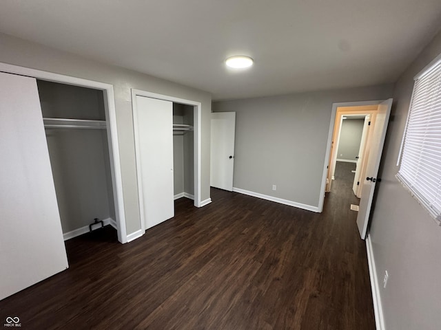 unfurnished bedroom featuring two closets and dark hardwood / wood-style floors