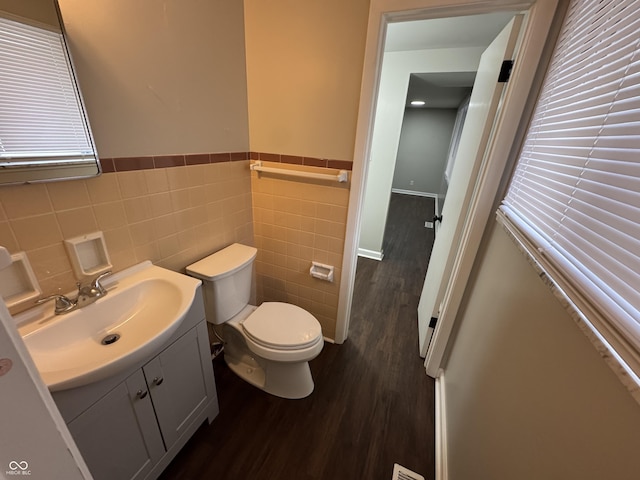 bathroom with hardwood / wood-style floors, vanity, toilet, and tile walls