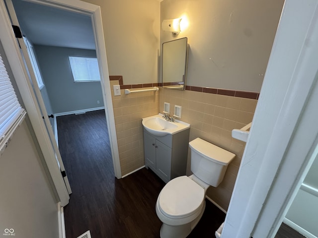 bathroom with hardwood / wood-style floors, vanity, tile walls, and toilet