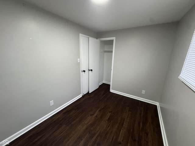 unfurnished bedroom with a closet and dark wood-type flooring