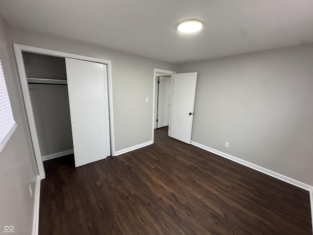 unfurnished bedroom featuring a closet and dark wood-type flooring