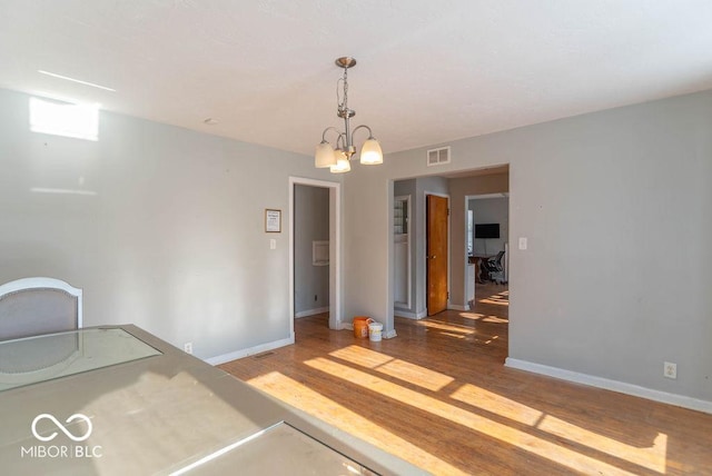 unfurnished dining area with light hardwood / wood-style floors and a notable chandelier