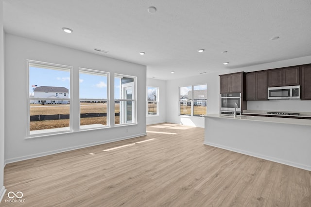 interior space with visible vents, baseboards, recessed lighting, light wood-style flooring, and a sink