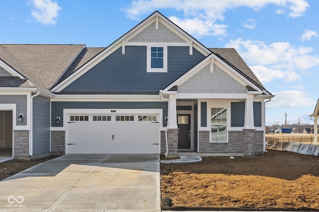 craftsman-style house with concrete driveway, a garage, fence, and stone siding