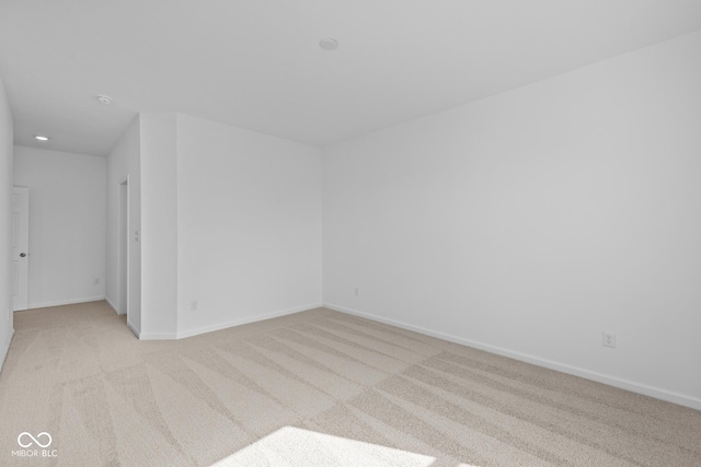 empty room featuring light carpet, recessed lighting, and baseboards