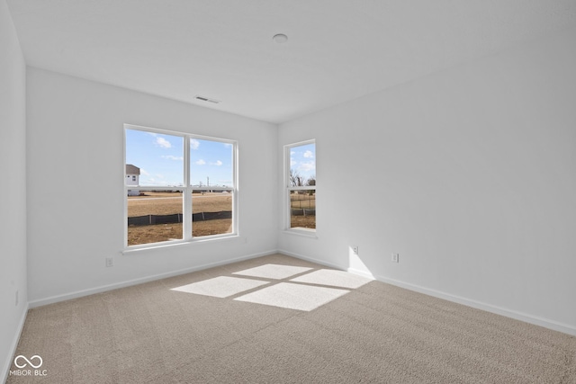 carpeted spare room featuring visible vents and baseboards