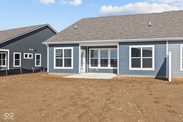 back of property with a patio and roof with shingles