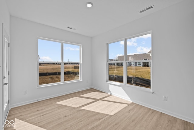 unfurnished room featuring visible vents, baseboards, and wood finished floors