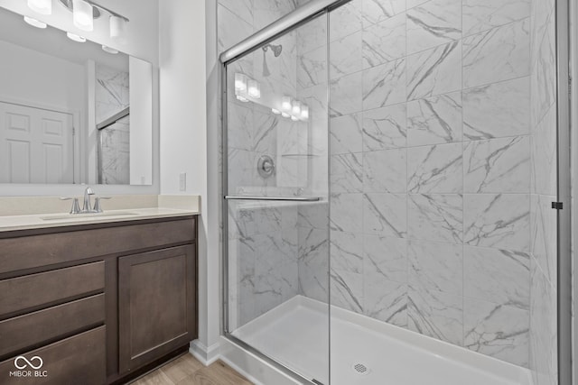 full bath featuring vanity, wood finished floors, and a marble finish shower