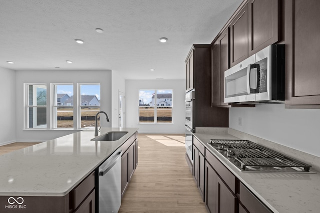 kitchen featuring dark brown cabinetry, light wood-type flooring, appliances with stainless steel finishes, and a sink