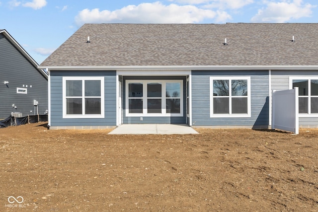 rear view of property with roof with shingles and a patio area