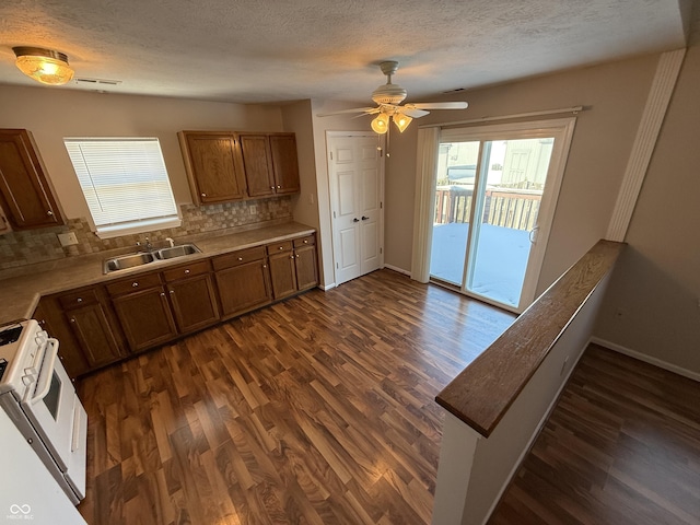 kitchen featuring sink, decorative backsplash, dark hardwood / wood-style floors, a textured ceiling, and white range oven