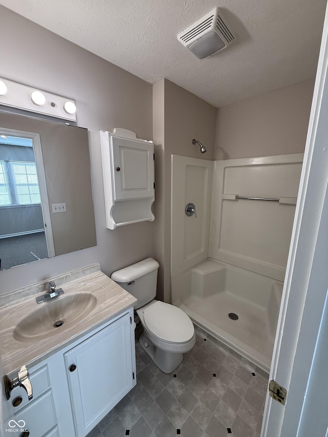 bathroom with vanity, a textured ceiling, and walk in shower