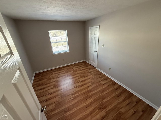 empty room featuring a textured ceiling and hardwood / wood-style flooring