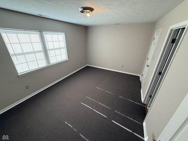 carpeted empty room featuring a textured ceiling