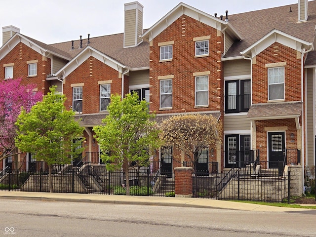 6595 Reserve Dr, Indianapolis, IN 46220 - view of front facade with brick siding, a shingled roof, and a fenced front yard
