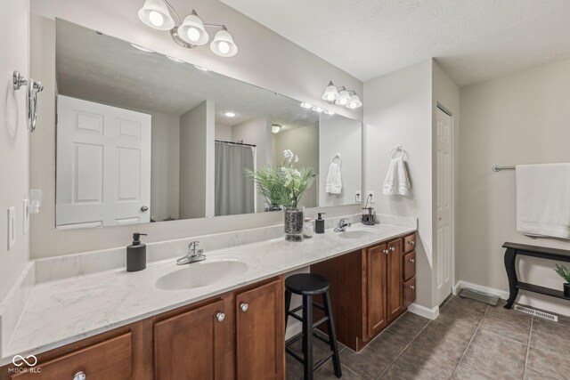 6595 Reserve Dr, Indianapolis, IN 46220 - bathroom featuring double vanity, tile patterned flooring, baseboards, and a textured ceiling