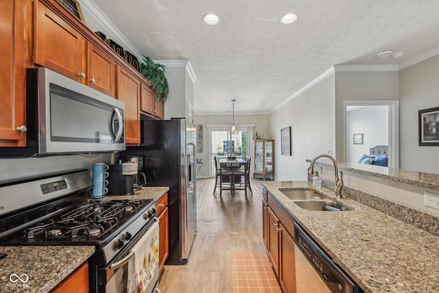 6595 Reserve Dr, Indianapolis, IN 46220 - kitchen with stainless steel appliances, a sink, brown cabinetry, light wood-style floors, and a textured ceiling